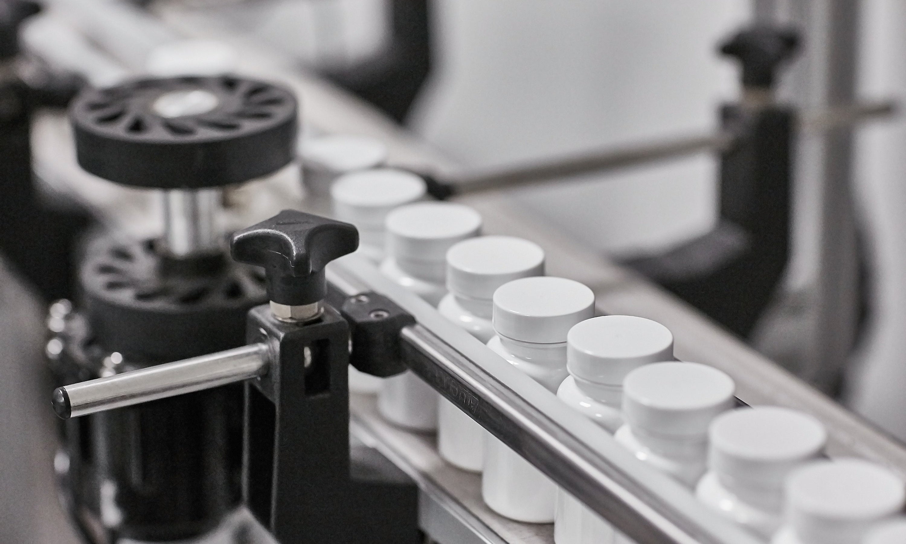 Supplement manufacturing line with white bottles on a conveyor belt