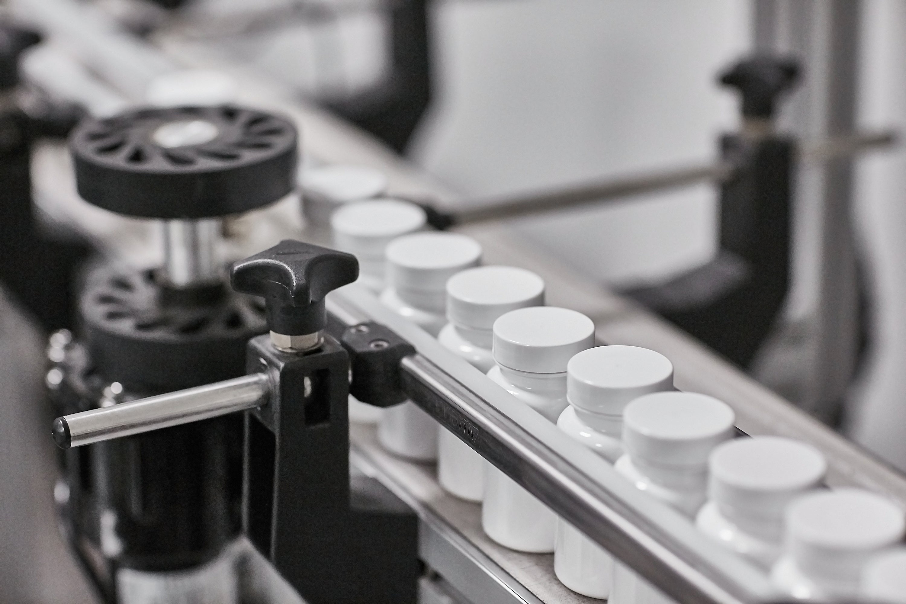 Supplement manufacturing line with white bottles on a conveyor belt
