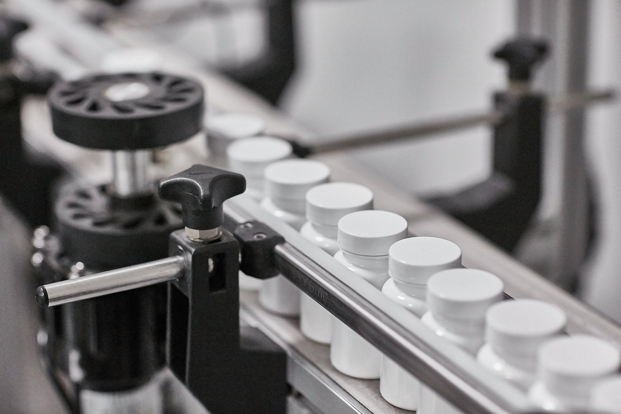 Supplement manufacturing line with white bottles on a conveyor belt